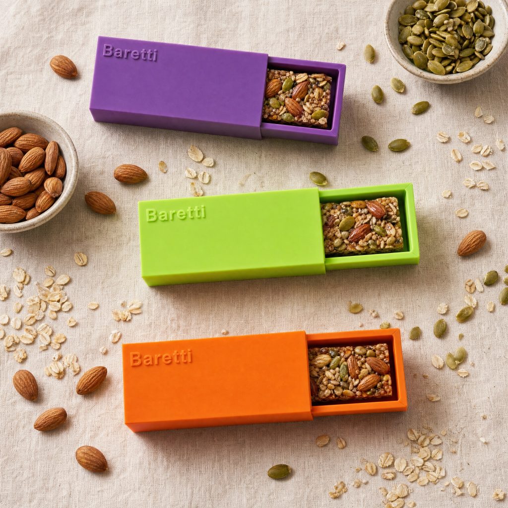 BarCraft reusable snack bar makers in purple, lime green, and orange displaying finished homemade nut and seed bars surrounded by raw almonds, oats, and pumpkin seeds